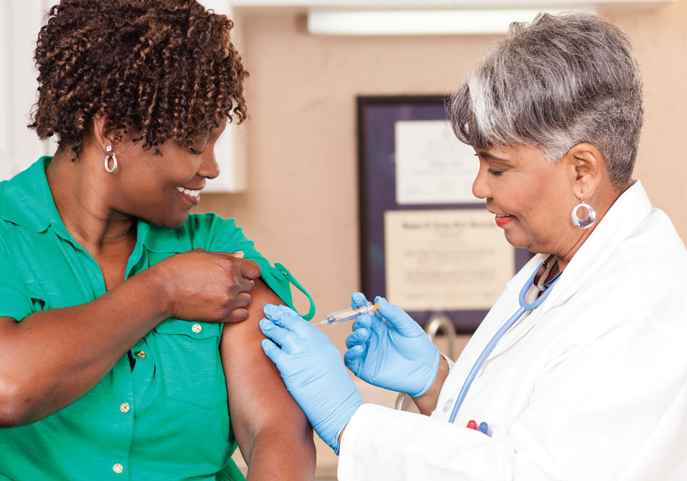 black female patient getting a vaccine from a black female nurse