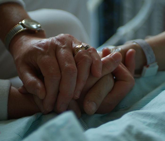 patient and caregiver holding hands