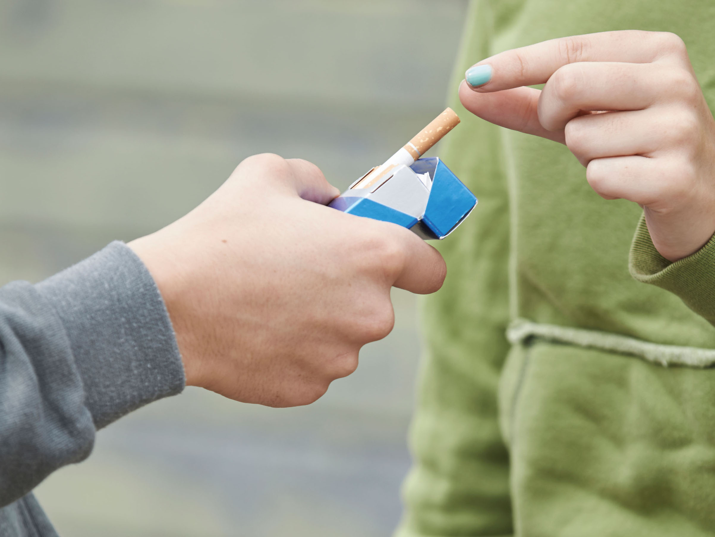 person's hand offering a cigarette to another person
