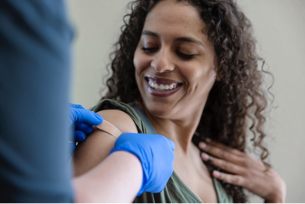 female patient getting a band-aid on shoulder after vaccination