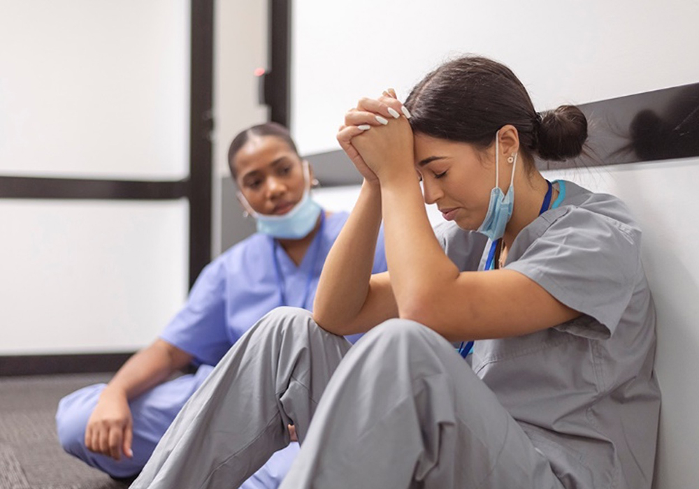 nurses sitting on floor with head in hands
