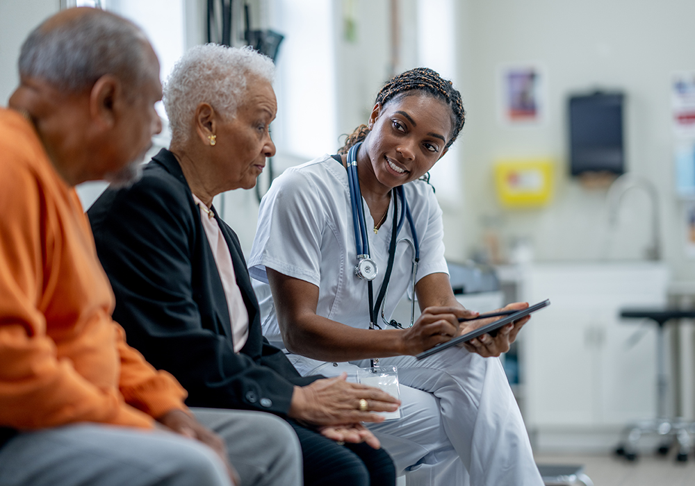 black nurse sitting with elderly black couple