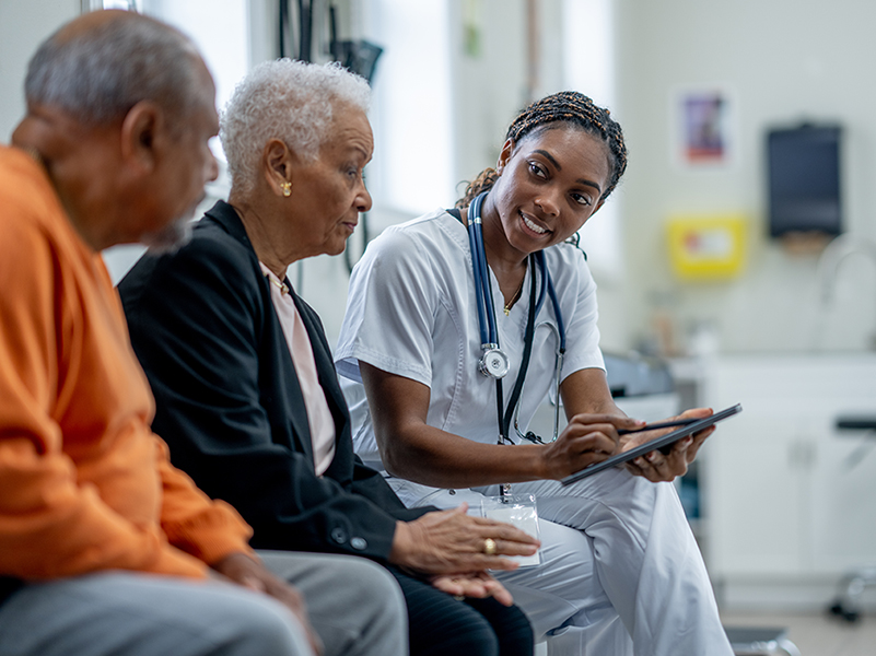 black nurse sitting with elderly black couple