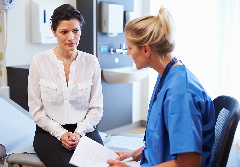 Nurse sits with patient in an exam room