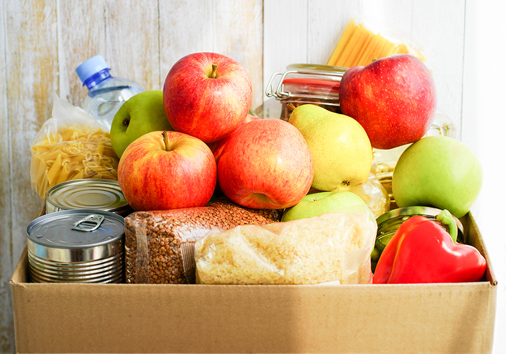 a box of fruits, vegetables, pasta, and canned goods