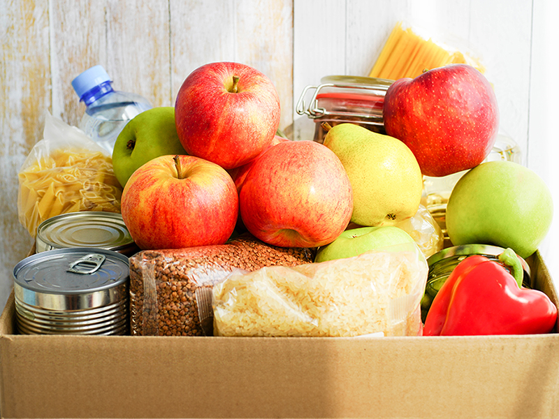 a box of fruits, vegetables, pasta, and canned goods