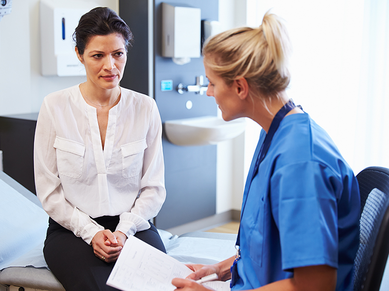 Nurse sits with patient in an exam room