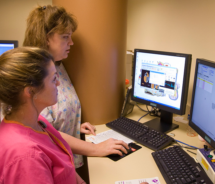 Two oncology nurses read a computer screen